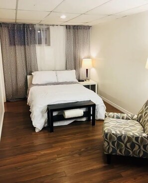 Relax in this inviting space with a comfortable bed, a bedside table, and a cozy armchair.
