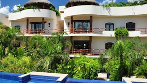 A resort with two-story buildings, a swimming pool, and lush tropical vegetation. - Steps from Beach,  Large private balcony overlooking pool & tropical garden (Playa del Carmen)