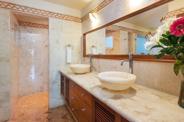 A bathroom with a marble vanity, two sinks, a shower, and a large mirror.