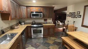 A kitchen with wooden cabinets, a microwave, a stove, and a sink. - Buttes Condo, Steps from the base area, Mountain Luxury (Crested Butte)