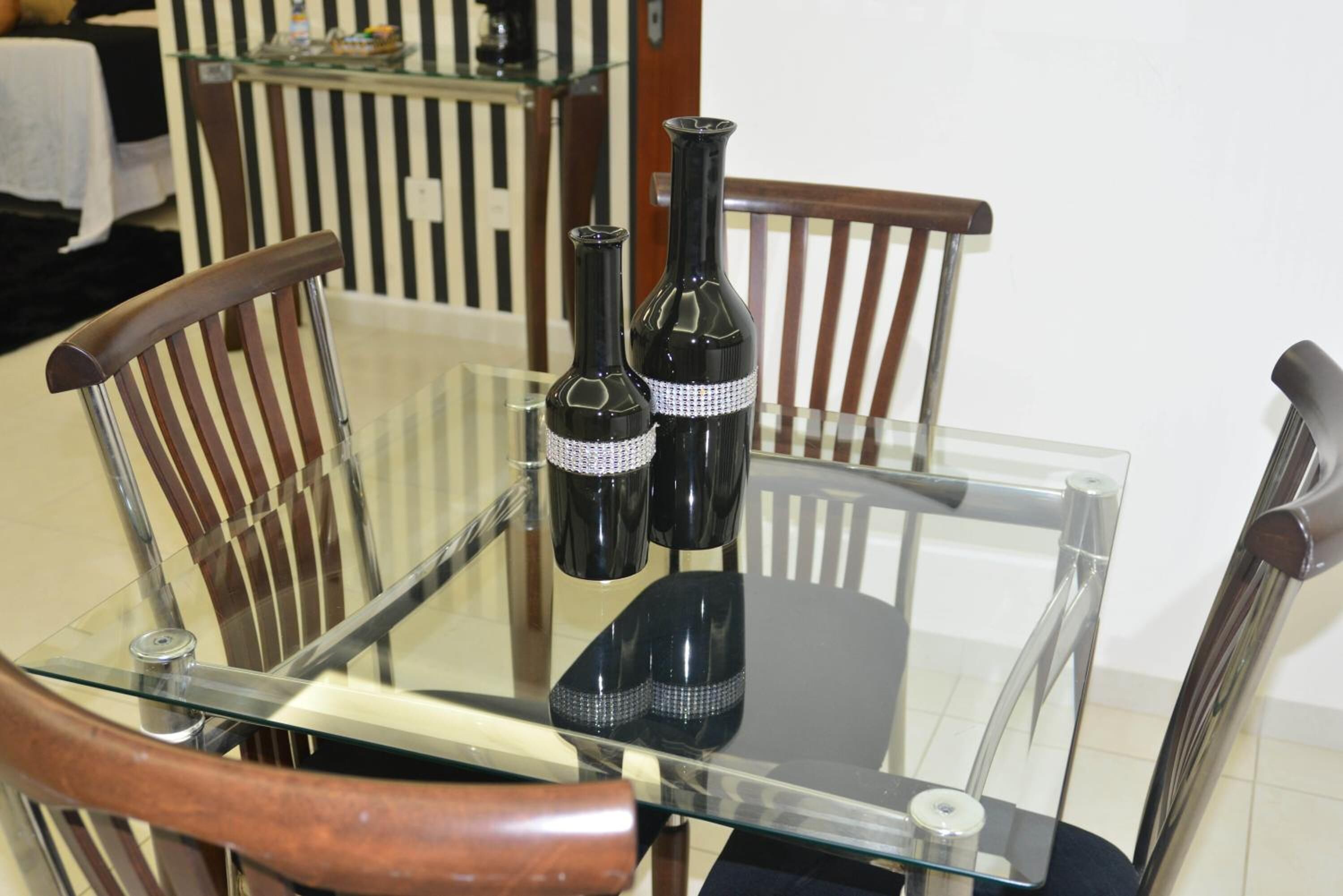 A glass-top dining table with two wine bottles and a decorative item.