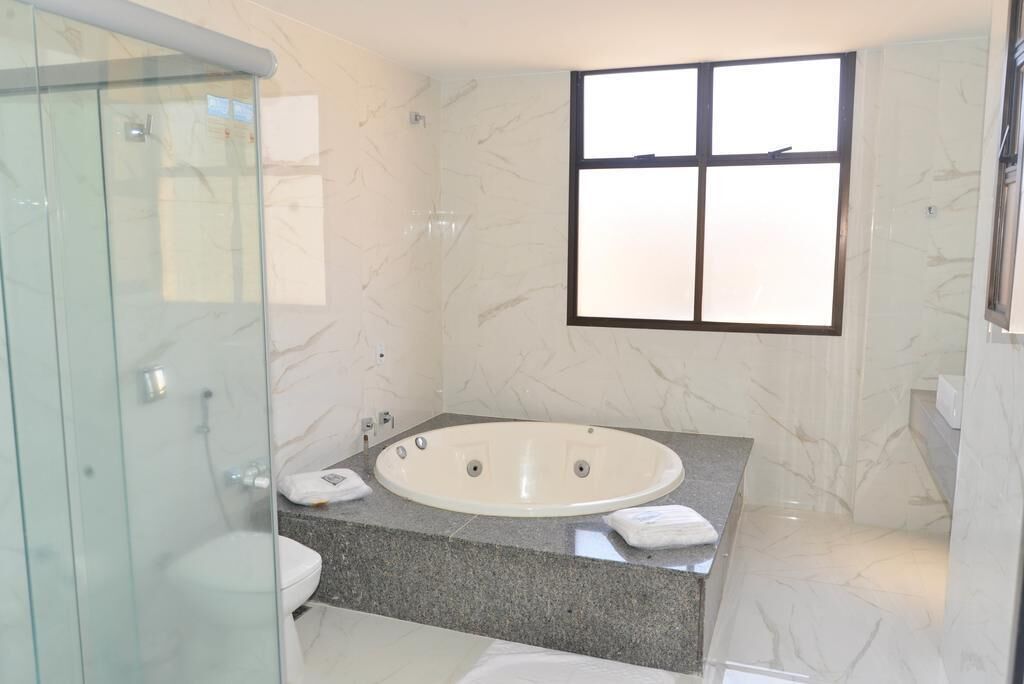 A modern bathroom with a glass-enclosed shower, a freestanding bathtub, and a marble-tiled wall.