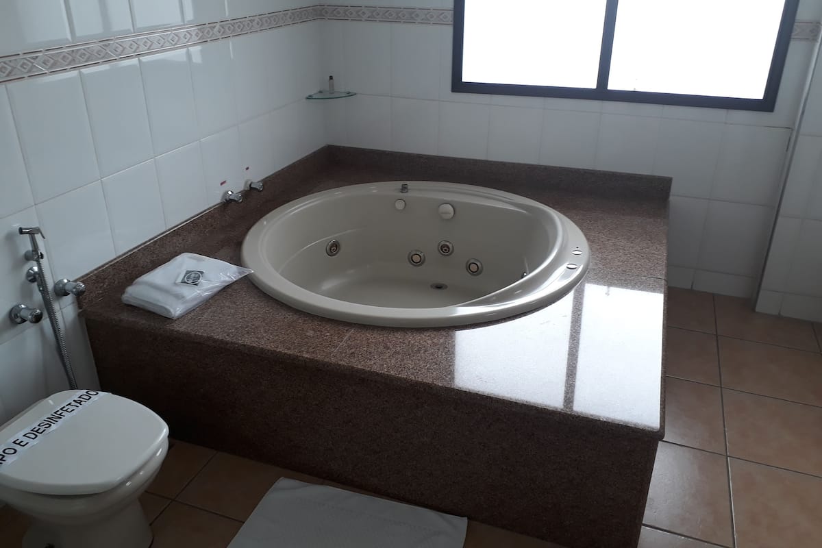 A bathroom with a bathtub, toilet, and a window.
