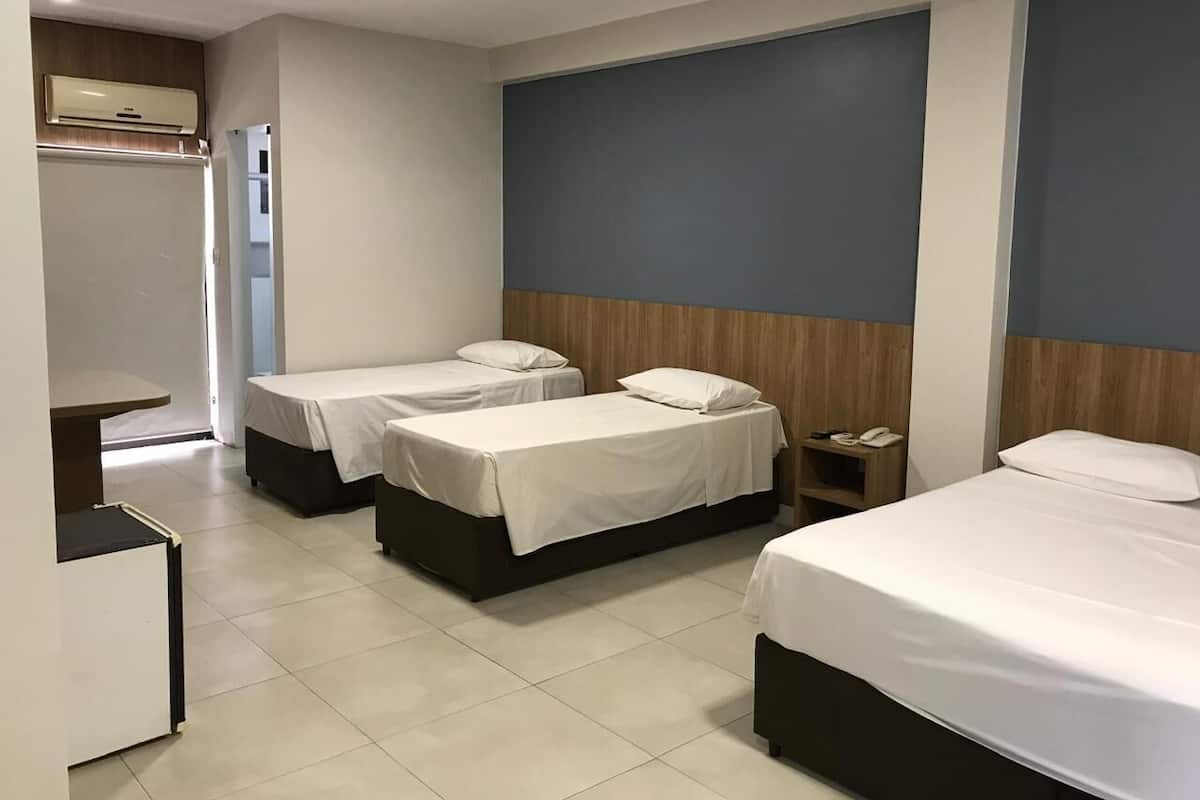 A hotel room with two single beds, a small bedside table with a phone, and a desk with a chair.