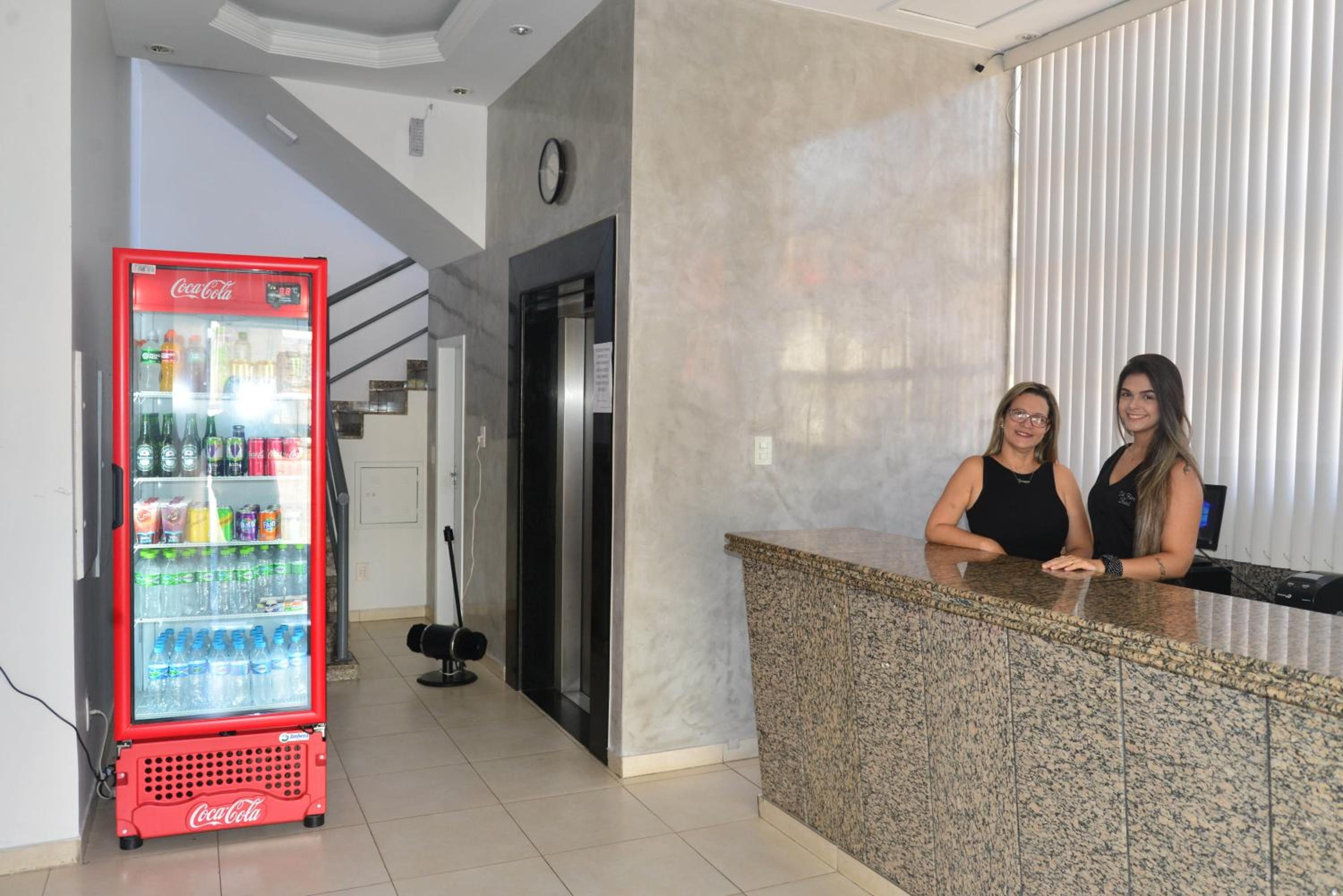 Un espace d’accueil doté d’un réfrigérateur Coca-Cola rempli de boissons, d’un ascenseur moderne et d’un comptoir en granit.