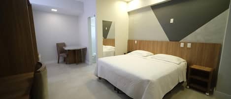 Una habitación de hotel moderna con una cama, mesitas de noche, un escritorio y una silla.
