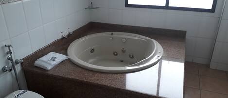 A bathroom with a bathtub, toilet, and a window.