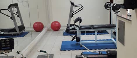 A gym with exercise equipment, a treadmill, a stationary bike, and a rowing machine.