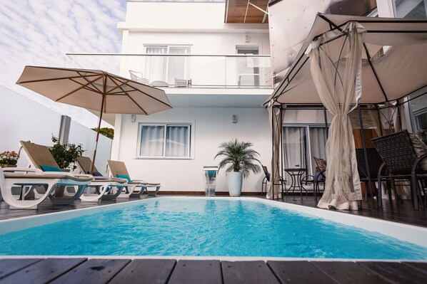 Een buitenzwembad, parasols voor strand/zwembad