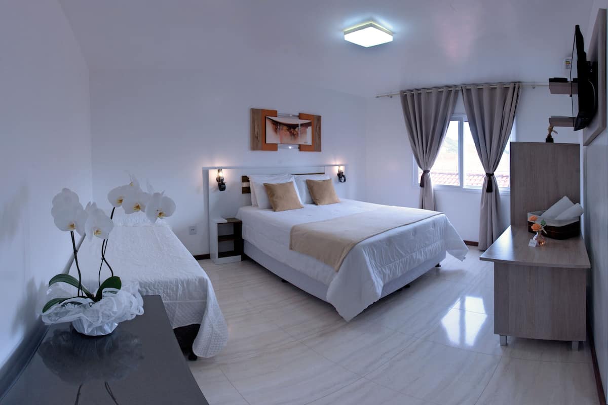 A modern hotel room with a large bed, bedside tables, a desk, and a TV.