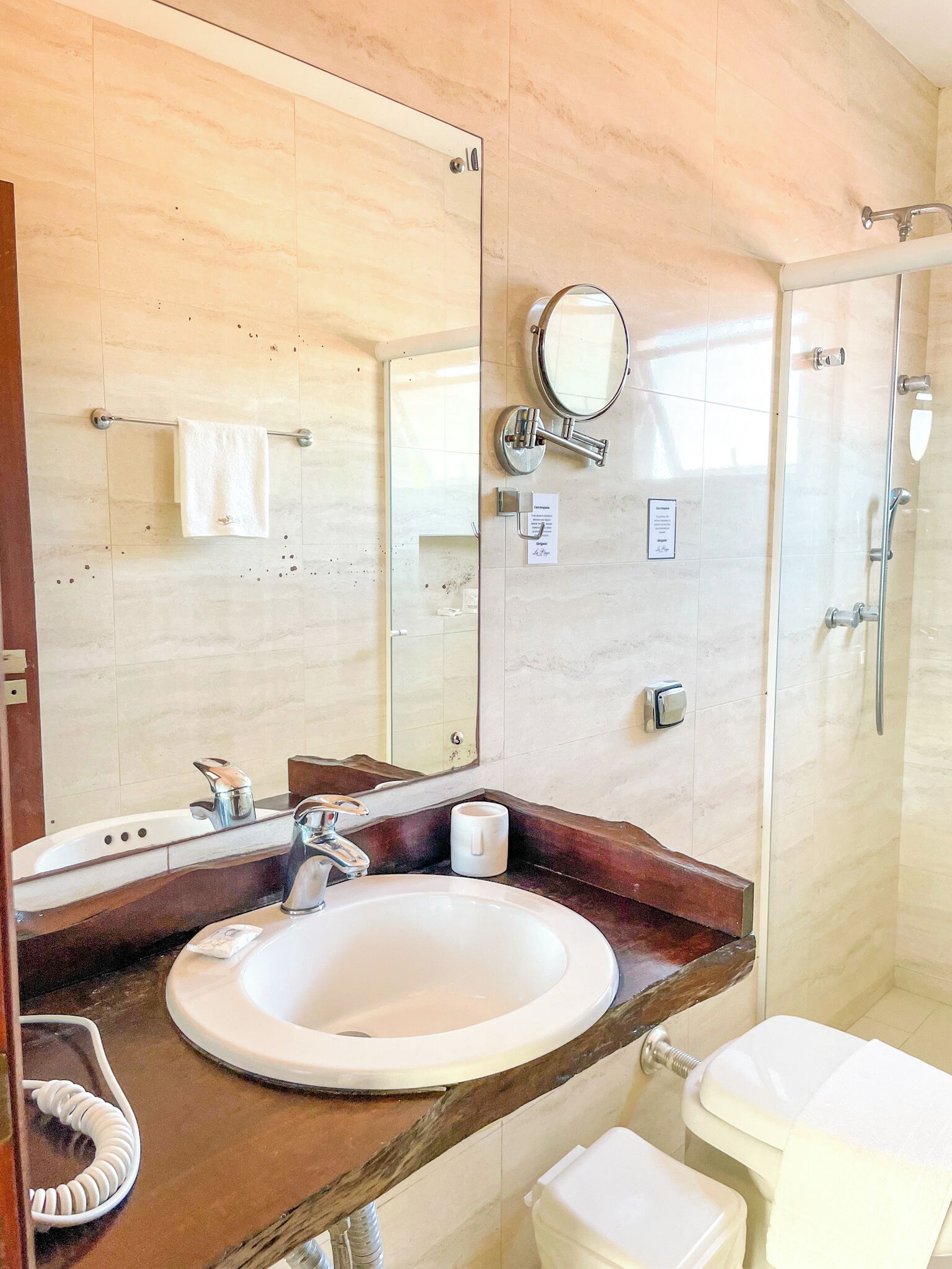 A bathroom with a sink, mirror, towel rack, and shower.