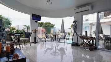 Una sala de estar moderna con televisor de pantalla plana, mesa de billar y mobiliario de exterior.