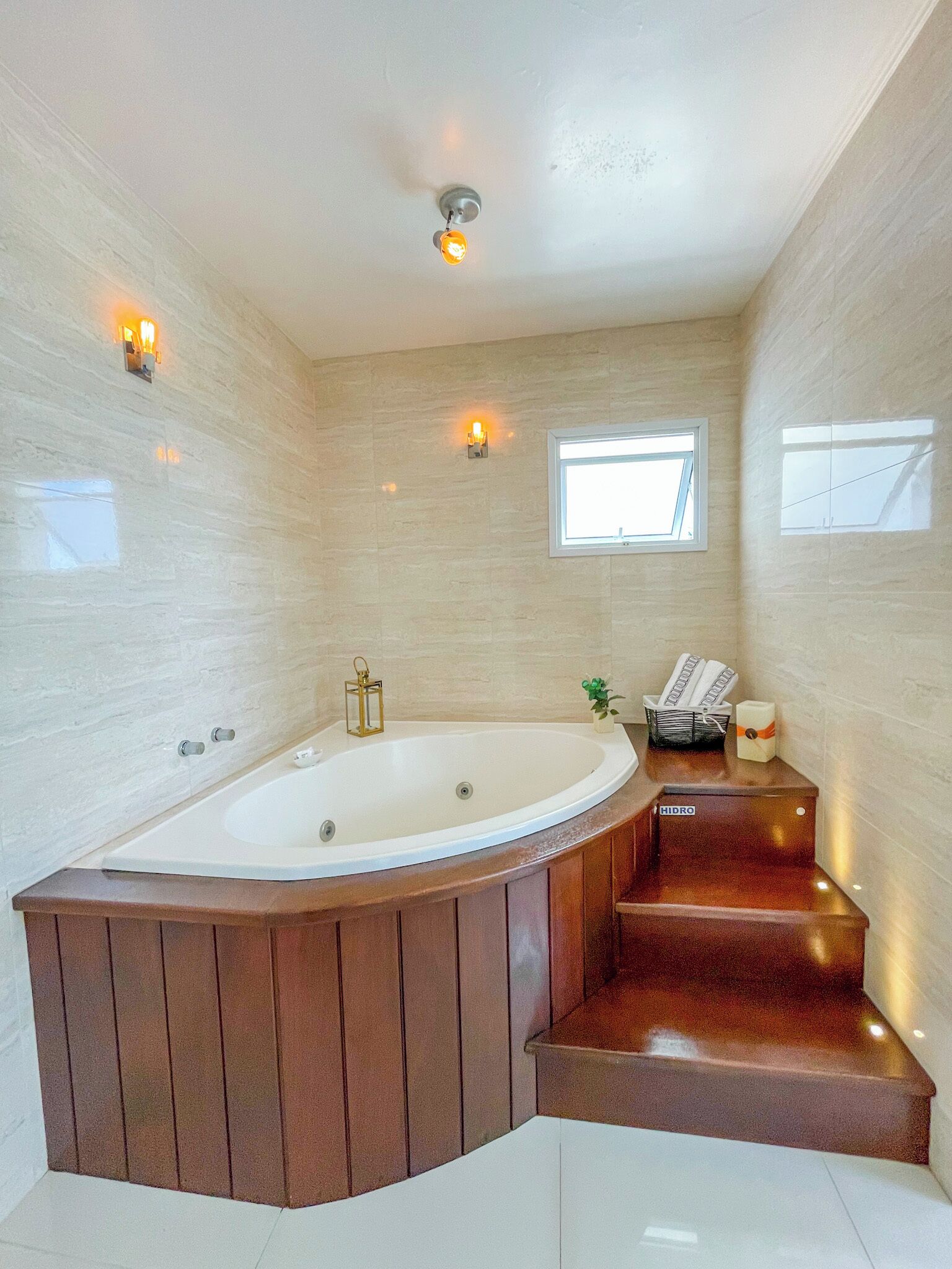 A spacious bathroom with a large freestanding bathtub, a window, and a small plant.