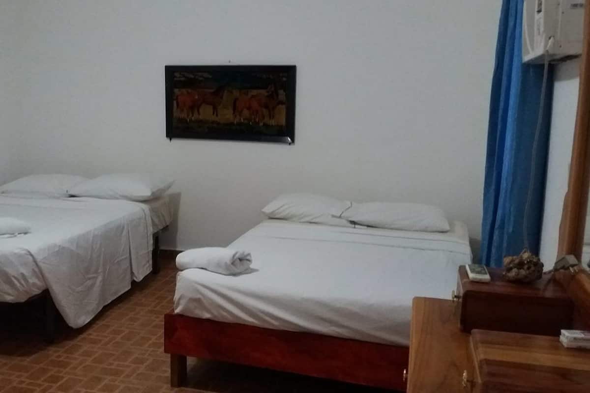 Ein Zimmer mit zwei Einzelbetten, einem Holznachttisch, einem kleinen Tisch und einer Wand-Klimaanlage.