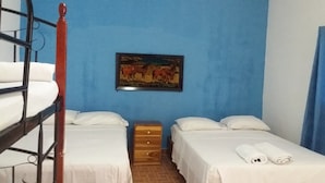 A room with two beds, a wooden dresser, and a painting of horses on the wall. - Hospedaje Yaquelin (Cambutal)