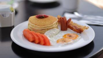 Un plat de petitdejuni amb crepes, ous, bacon i pastanagues.