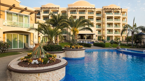 A hotel with a swimming pool, palm trees, and a well-maintained garden. - Diamond Bay (Mazatlán)