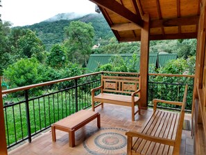 A wooden balcony with a bench and a table, overlooking a lush green landscape with trees and a mountain in the background. - Encanto Chalet-1.5 km from the center, 3 bedrooms, sleeps 8. Spectacular mountain view! (Monte Verde)