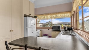 Une cuisine équipée d’un réfrigérateur, d’un four à micro-ondes et d’une cuisinière. Une fenêtre offre une vue sur l’extérieur.