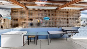 Een buitenkeuken met een blauwe bank, een tafel en een barbecue.