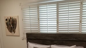 Ein ordentlich bezogenes Bett mit weißer Daunendecke und mehreren Kissen, ein hölzernes Kopfende und ein gemustertes Teppich.