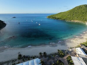 A coastal view with a beach, clear water, and boats.