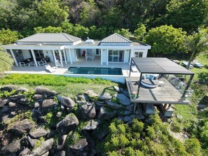 A modern two-story house with a swimming pool, outdoor seating, and a deck.