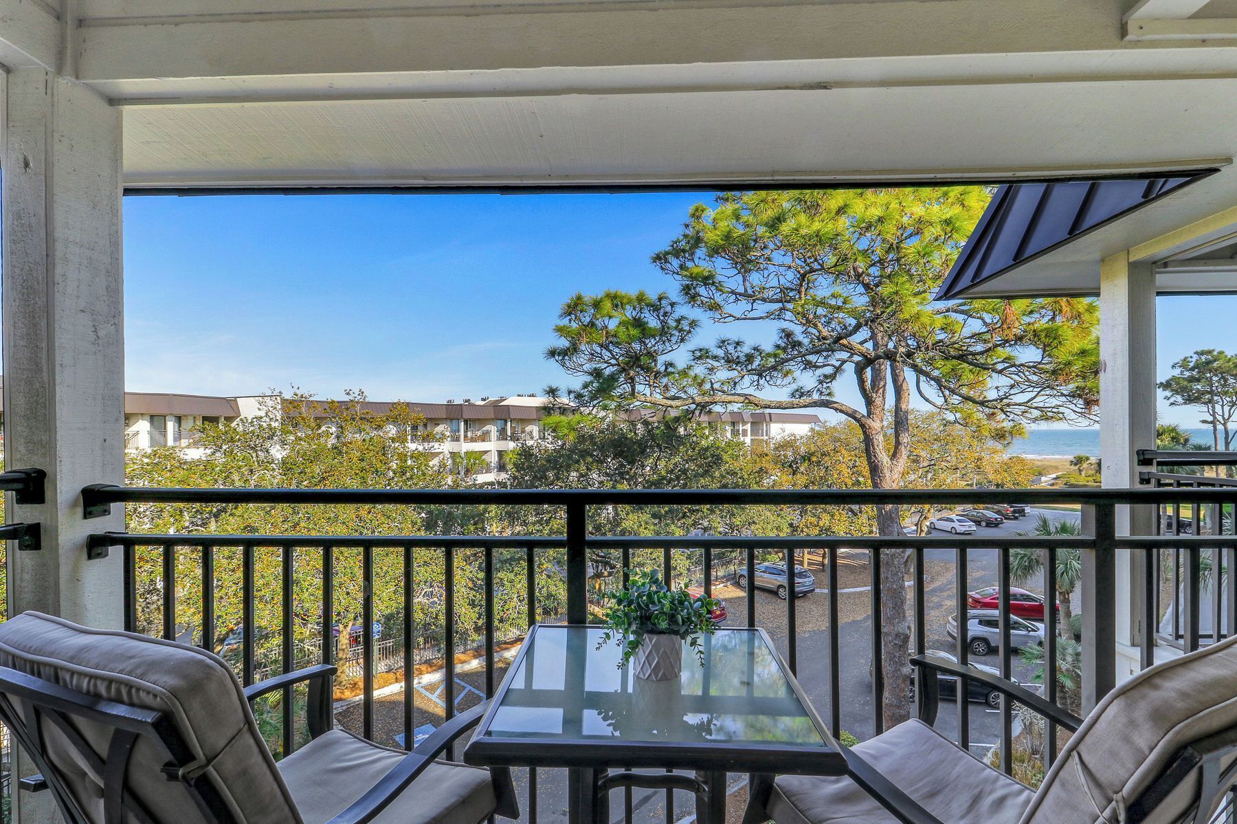 Ein Balkon mit Glastisch und Stühlen, der auf einen Parkplatz und einige Gebäude blickt.