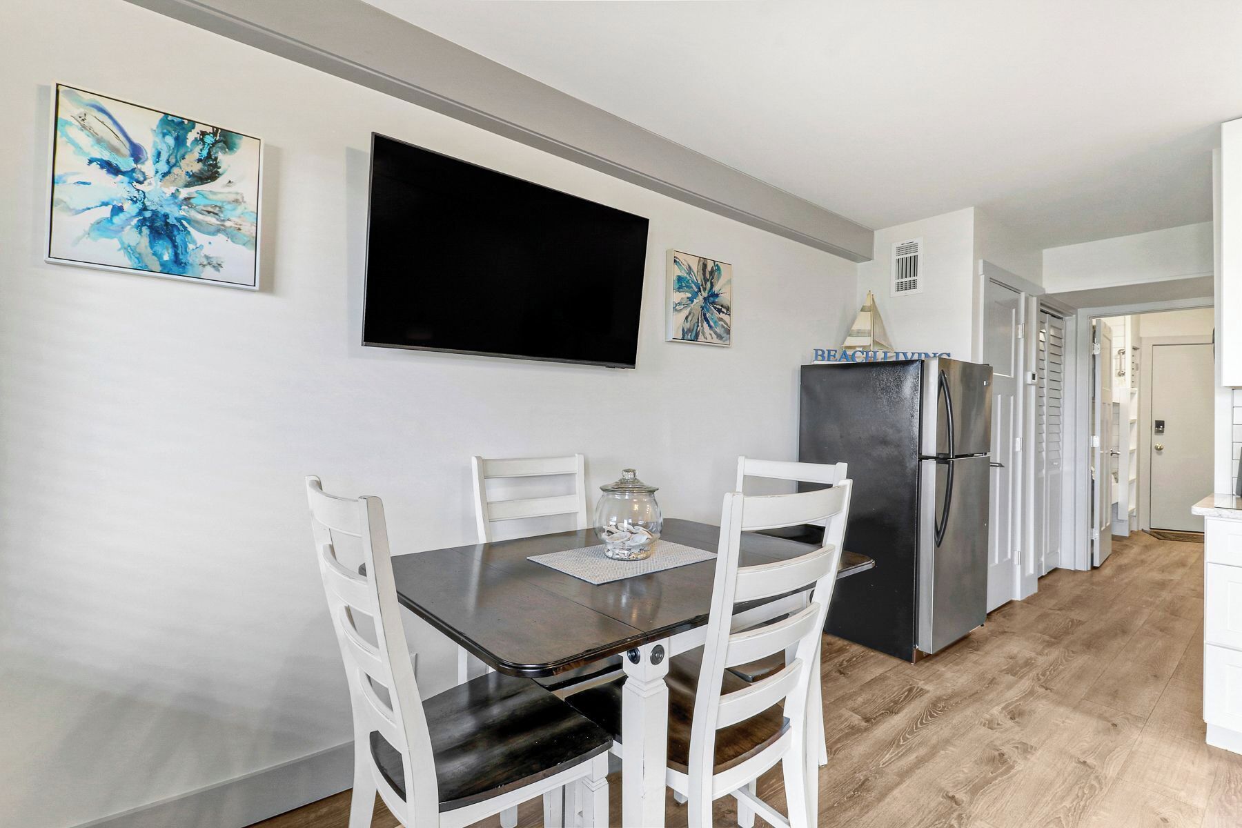 A dining area with a table, chairs, a TV, and a refrigerator.