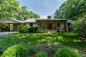 A two-story house with a covered porch, a front yard with a lawn and shrubs, and a garage.