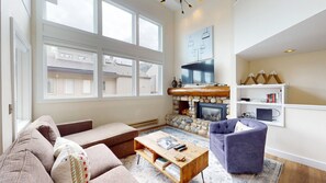 A living room with a stone fireplace, a television, and a bookshelf.