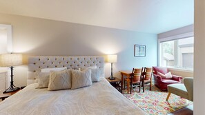 A bedroom with a large bed, two bedside lamps, a small table with chairs, and a window with a view. - Knob Hill Ridge Townhome 1 - Modern Decor Right in Downtown and Pet Friendly (Ketchum)