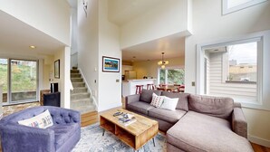 A spacious living area with a sofa, coffee table, and a staircase leading to a kitchen. - Knob Hill Ridge Townhome 1 - Modern Decor Right in Downtown and Pet Friendly (Ketchum)