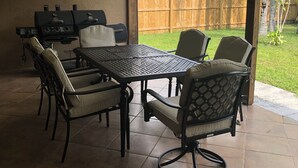 En patio med bord og stole, ventilator i loftet og grill.