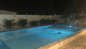 A swimming pool with a tiled border and a hose in the water.
