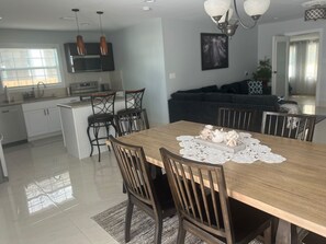 Een moderne keuken met een centraal eiland, een eettafel met stoelen, en een zithoek met een bank.