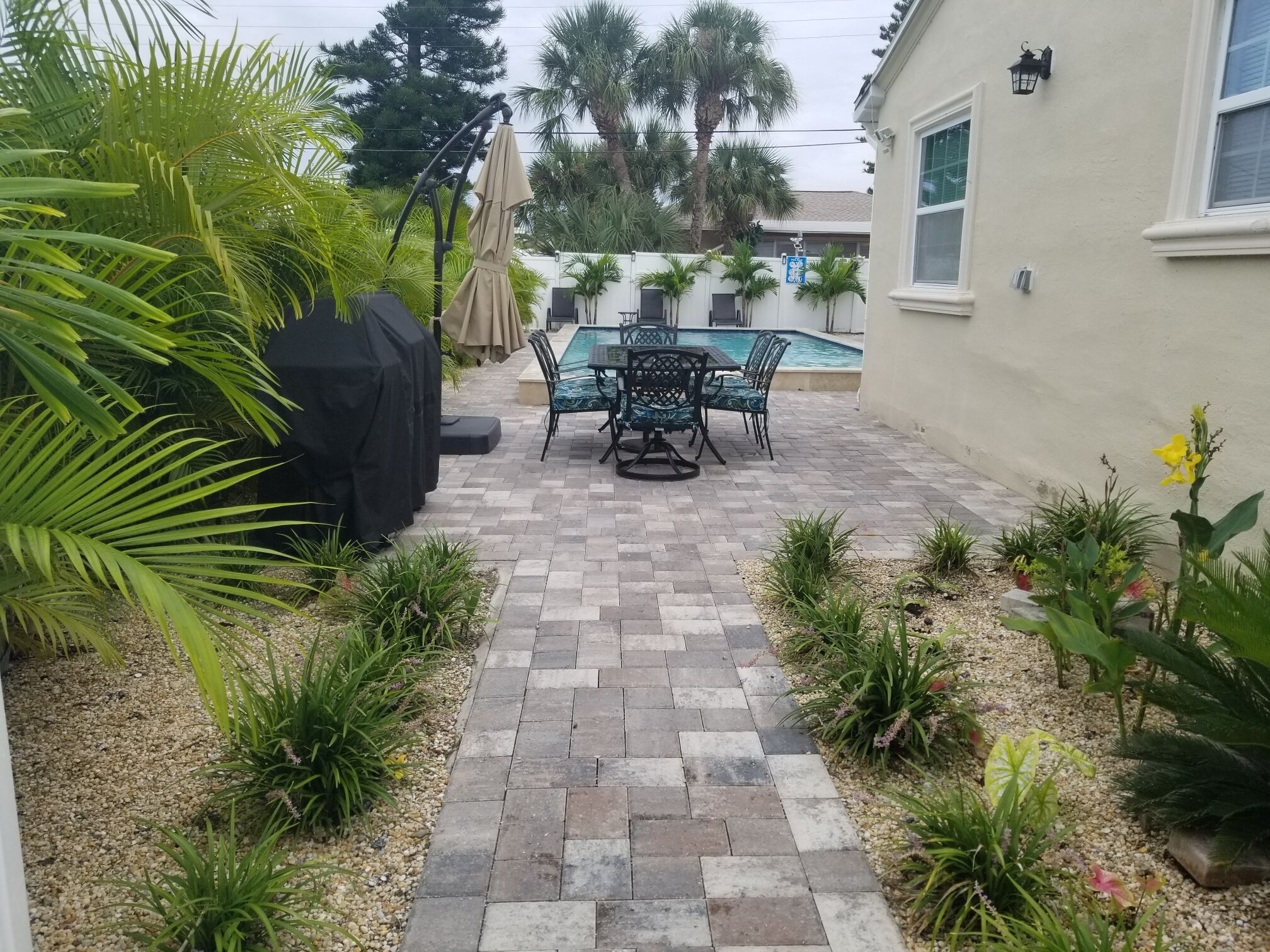 A patio area with a pool, outdoor furniture, and a variety of plants.