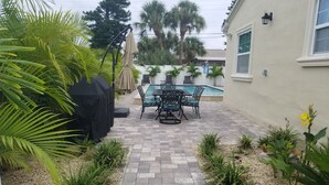 A patio area with a pool, outdoor furniture, and a variety of plants.