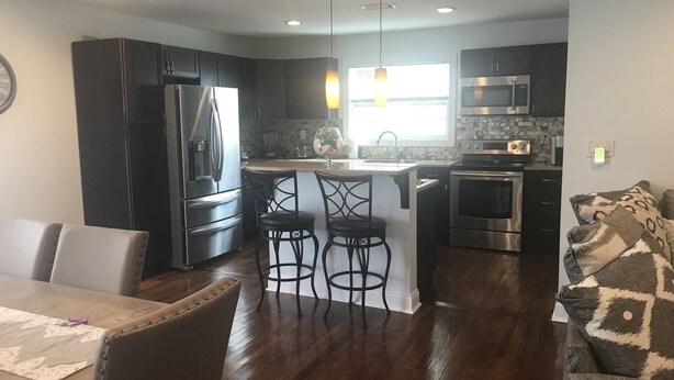 A modern kitchen with dark cabinetry, stainless steel appliances, and a central island with bar stools.