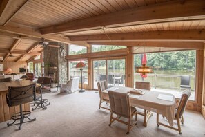 A spacious room with a large dining table, comfortable seating, and a view of a lake through large windows. - A Private Dock. A Lake That Goes Quiet After Sunset | Sequoyah Lakeside Lodge (Highlands)