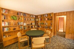 A library with wooden bookshelves, a round table, and four chairs.