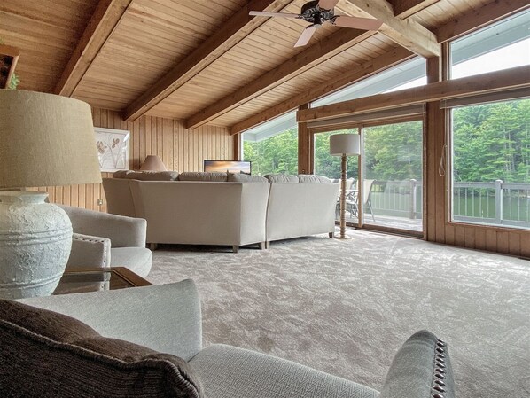 Una habitación amplia con techo alto, un ventanal con vistas al exterior, un sofá y una lámpara.