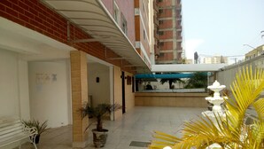 A hotel corridor with tiled flooring, potted plants, a bench, and a fountain. - Kit to enjoy the beach, holidays and vacations  (Praia Grande)