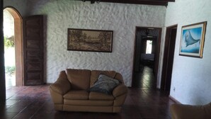 Un salón amplio con un sofá de cuero marrón, una alfombra y un cuadro en la pared.