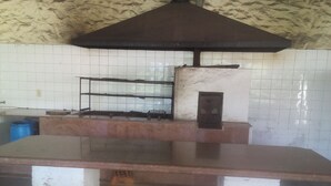Una cocina con una encimera grande, una estantería metálica y una campana extractora.