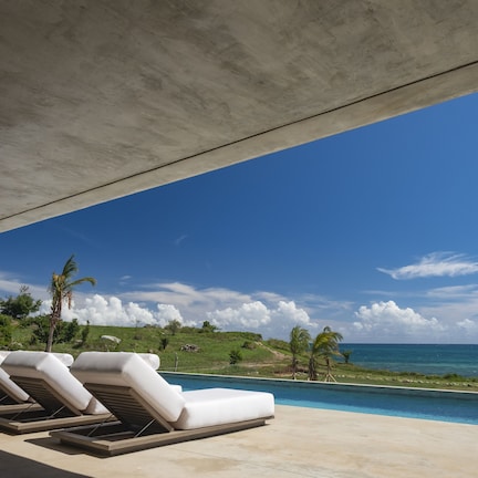 A poolside area with lounge chairs and a view of the ocean.