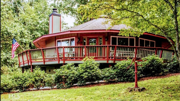 Une maison à l’extérieur rouge, dotée d’un balcon avec une balustrade et arborant un drapeau américain.