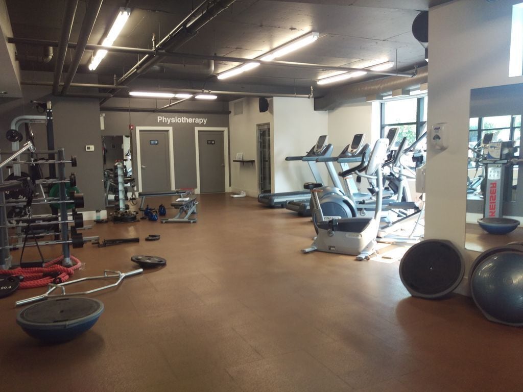 Un gimnasio con cintas de correr, máquinas de pesas y una sala de fisioterapia.