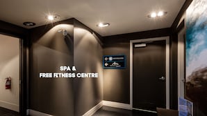 A hallway with a sign for a spa and free fitness centre, a fire extinguisher, and a door.