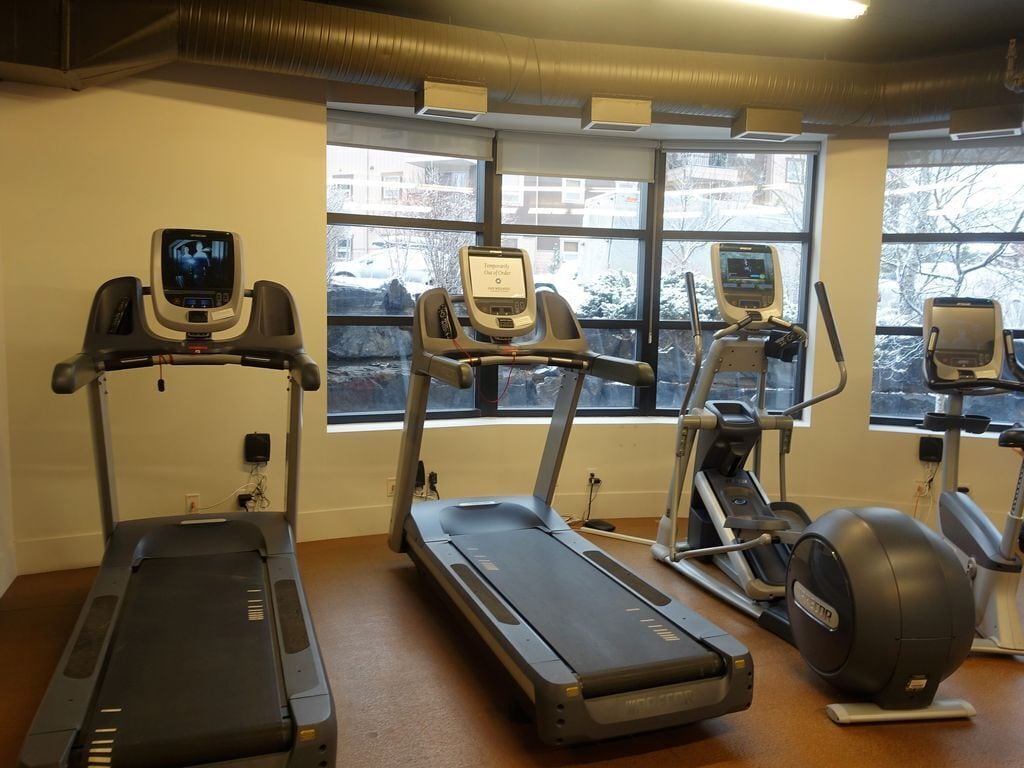 Ein Fitnessstudio mit Laufbändern, Crosstrainern und einem Ergometer.